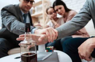 man preventing another to reach bottle of liquour
