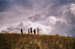 People Standing on Hill Looking at Clouds